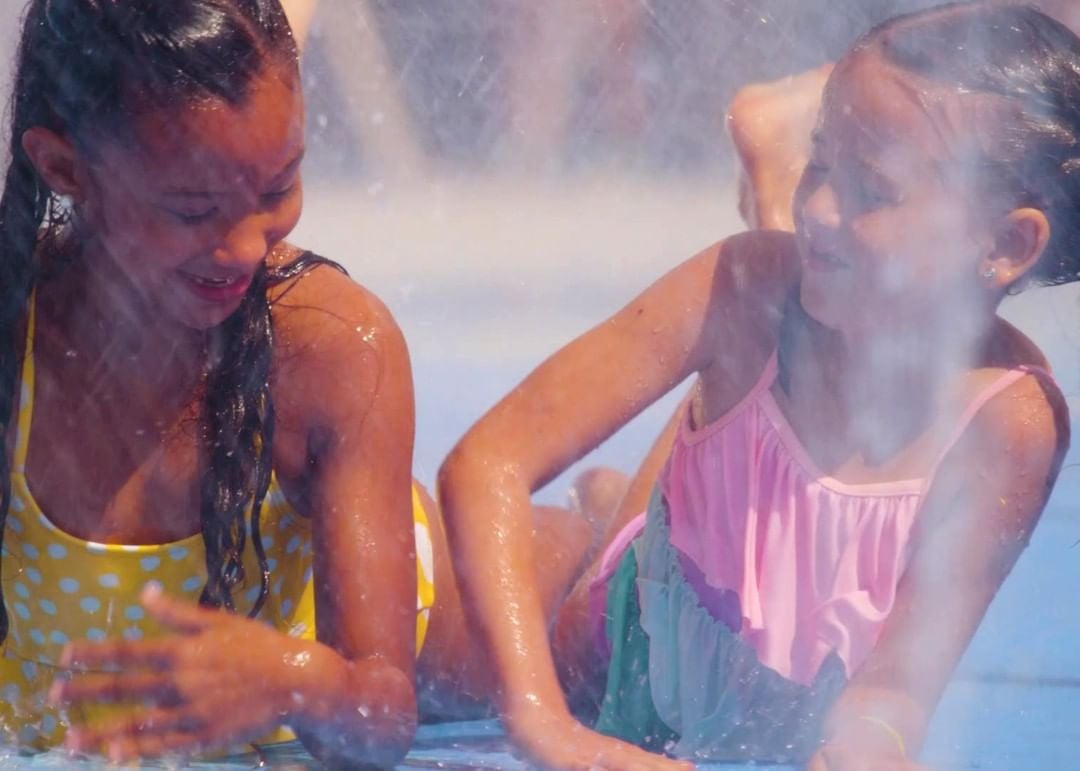 Two laughing young girls playing in the water