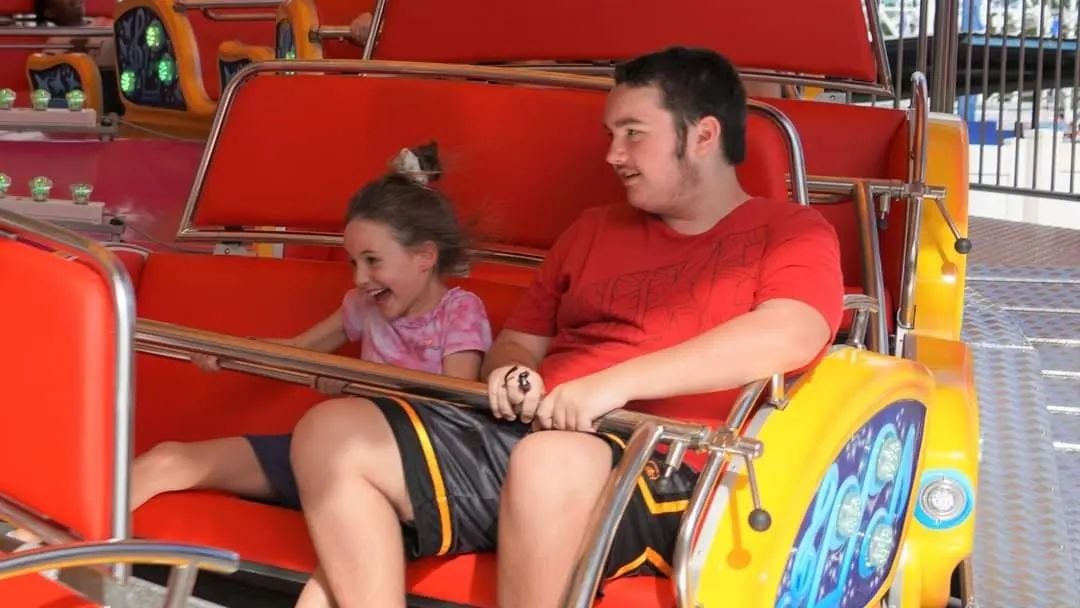Teenager and young child riding the Rock n Roll thrill ride