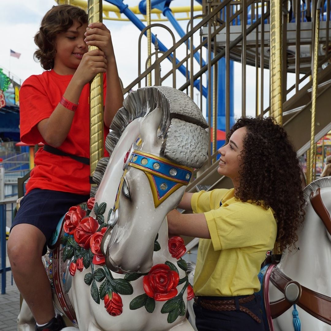 Smiling child riding a carousel horse