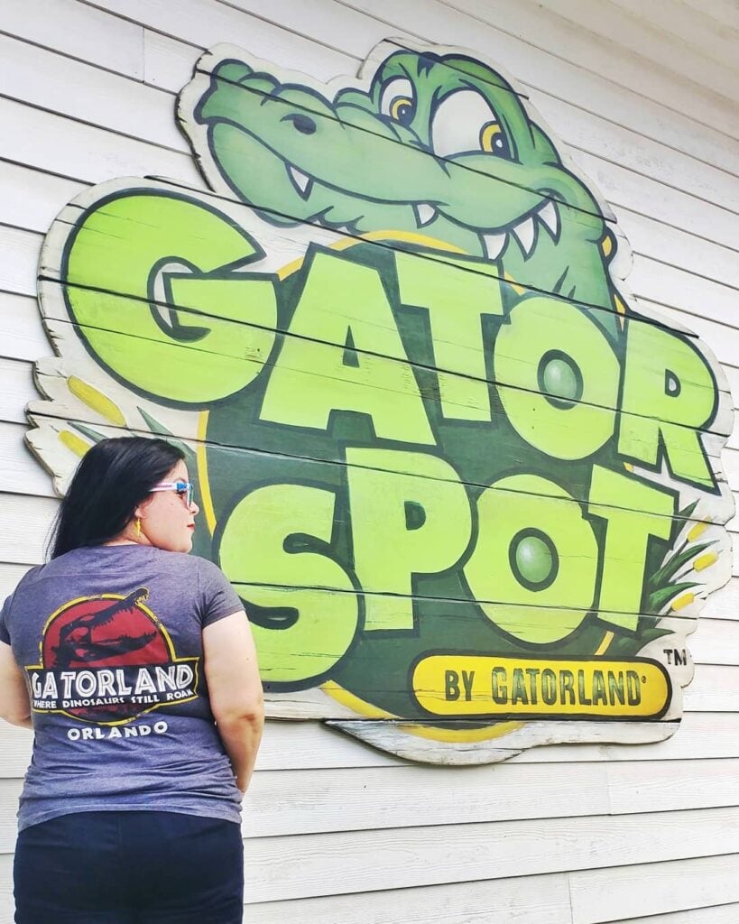 Woman standing next to Gator Spot by Gatorland sign