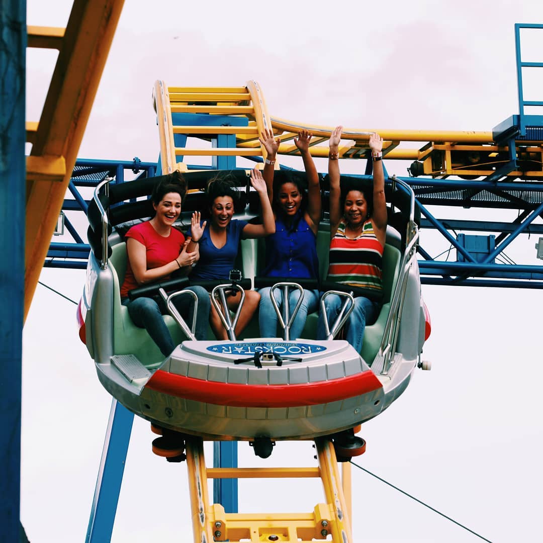 Four happy young women riding a roller coaster