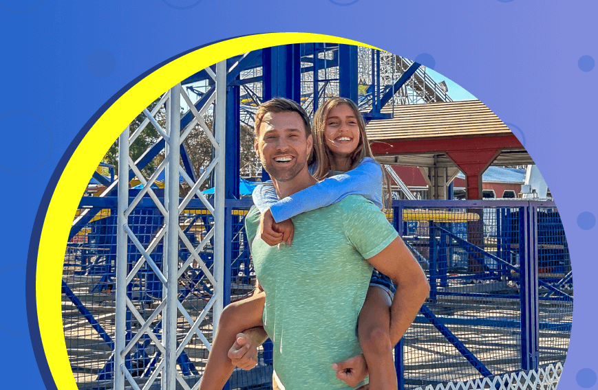 Man giving piggyback ride to smiling girl at amusement park
